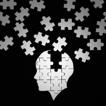 White jigsaw puzzle as a human brain on black. Huntington's Disease