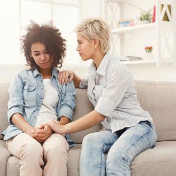 Two sad diverse women talking at home. Female friends supporting each other. Problems, friendship and care concept (Two sad diverse women talking at home. Female friends supporting each other. Problems, friendship and care concept, Speech Loss