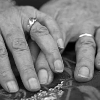 Hands of an elderly couple married for over 60 years heading to gray divorce