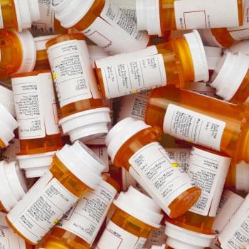 Dozens of prescription medicine bottles in a jumble. This collection of pill bottles is symbolic of the many medications senior adults and chronically ill people take.