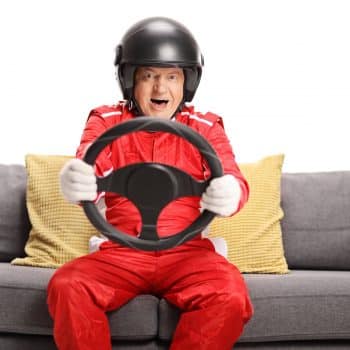 senior man holding steering wheel on couch