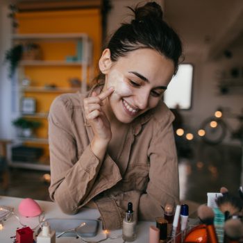 Young woman applying daily skin care cream