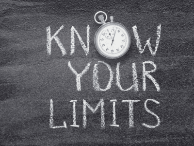 The phrase 'KNOW YOUR LIMITS' is written in white chalk on a black chalkboard, with a stopwatch placed above the word 'KNOW.' The stopwatch adds a sense of urgency or timing to the message, emphasizing the importance of understanding limits, possibly in the context of time-sensitive insurance claims or policies