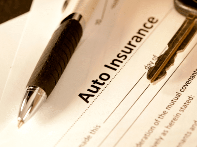 Pen and car key resting on an auto insurance document